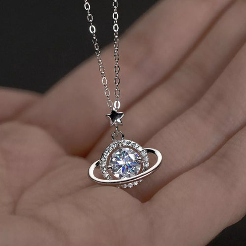 Silver necklace with a circular pendant held in a hand against a dark background