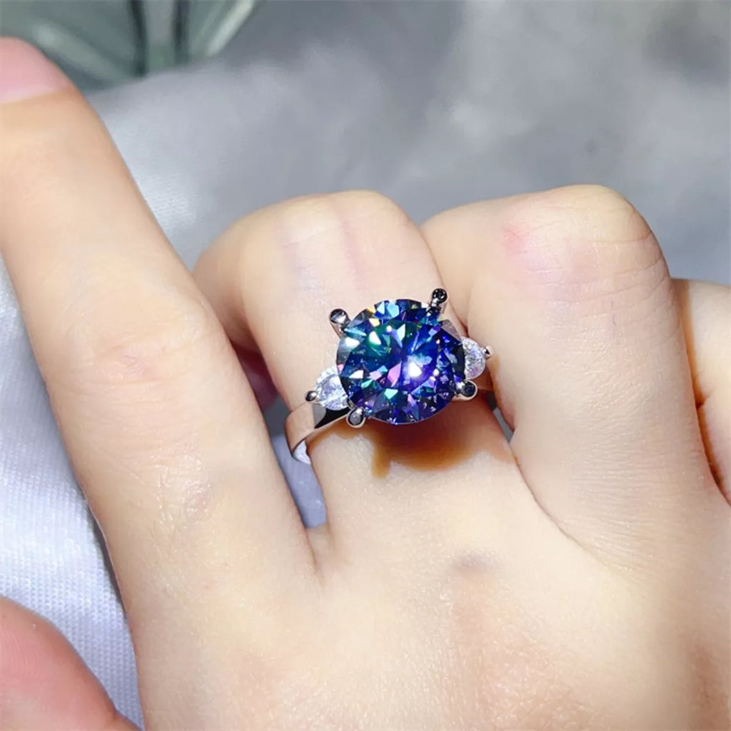 Blue moissanite diamond Ring with a colorful gemstone on a finger against a neutral background