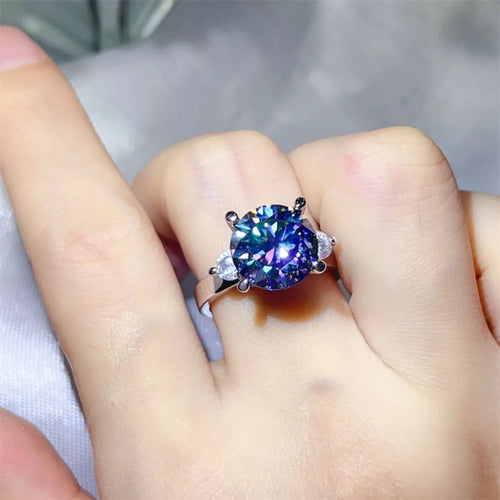 Blue moissanite diamond Ring with a colorful gemstone on a finger against a neutral background