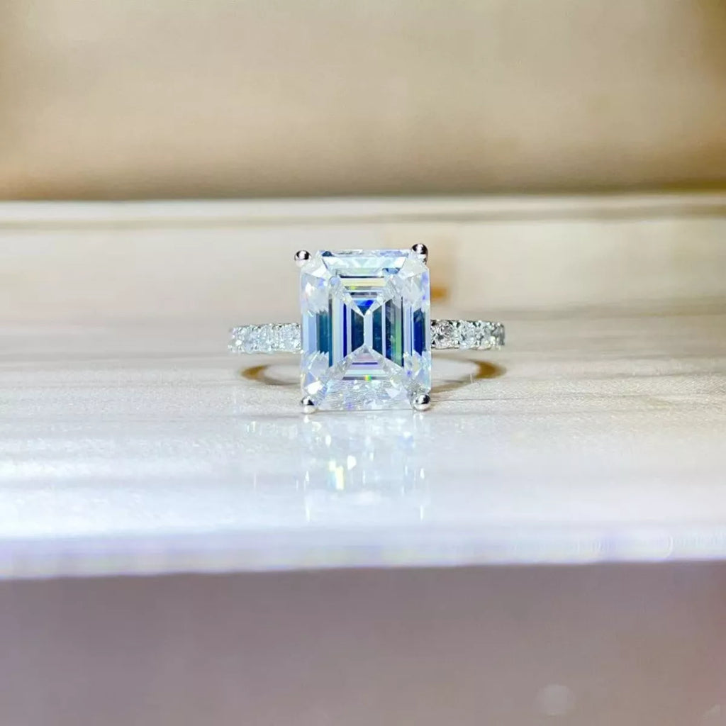 Moissanite Diamond ring with emerald-cut center stone on a reflective surface | Konfidential Kouture