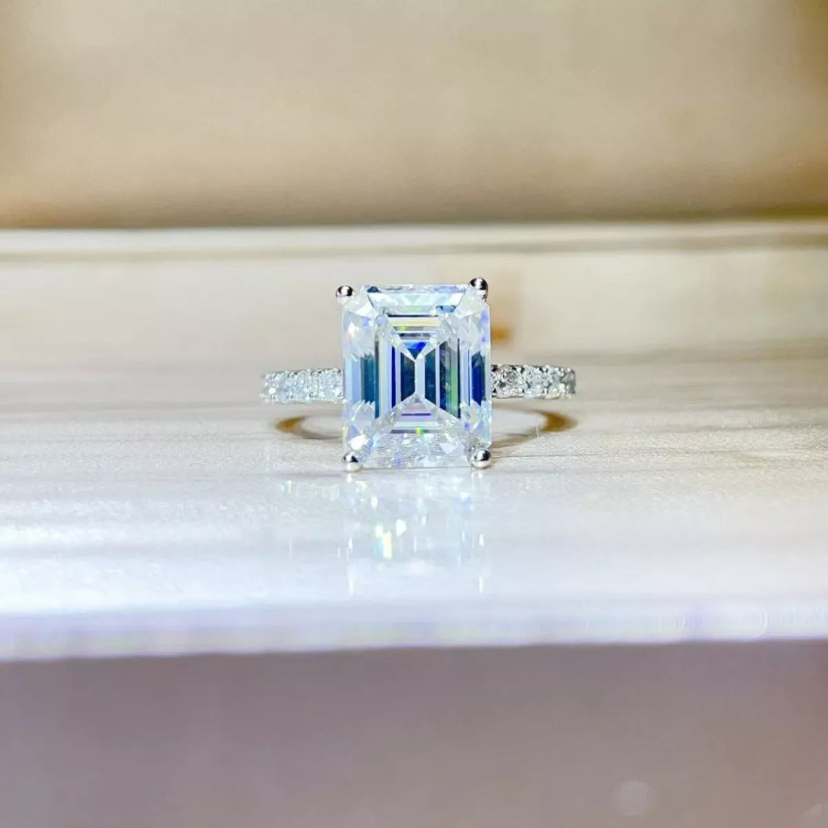 Moissanite Diamond ring with emerald-cut center stone on a reflective surface | Konfidential Kouture