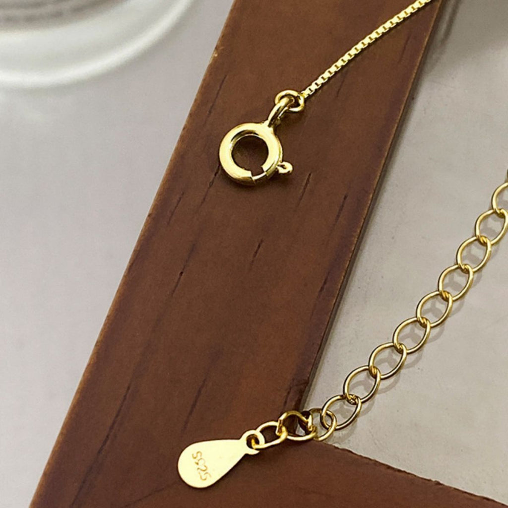 Gold necklace with a clasp on a wooden surface