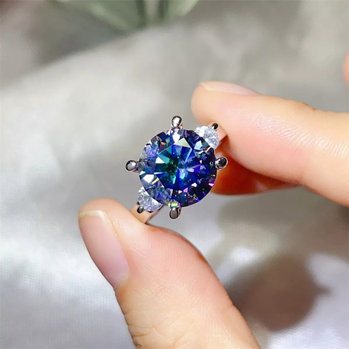 Close-up of a hand holding a diamond earring with a multicolored gemstone.