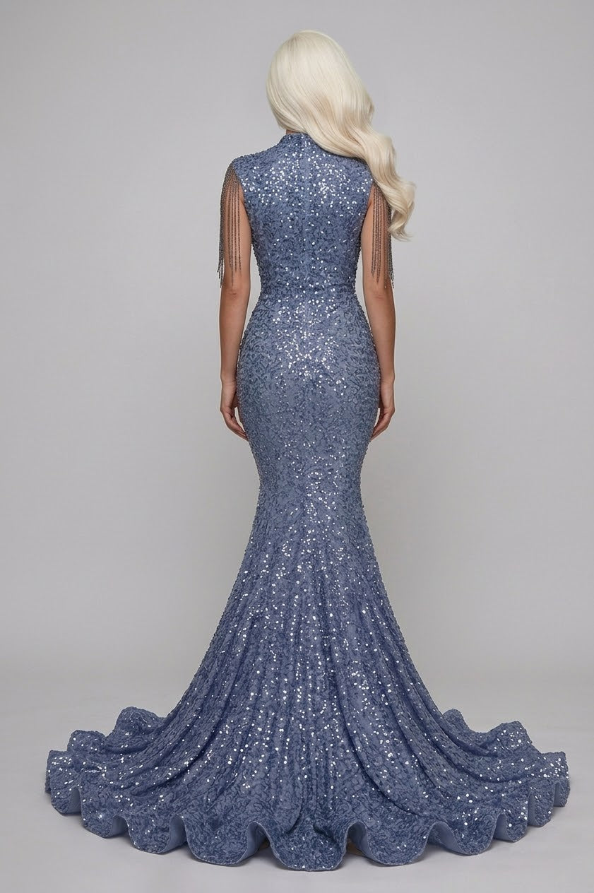 A woman shown from the back wearing a sleeveless, high-neck mermaid gown covered in shimmering blue sequins, with a long blonde wig, against a light gray studio background.