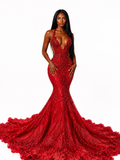 A woman modeling a deep red mermaid gown with intricate 3D floral embroidery and a dramatic train against a solid white background.