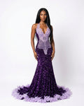 A model wearing a formal mermaid gown with a lavender lace bodice and a deep purple sequined skirt with a feathered hem, set against a plain white studio background.