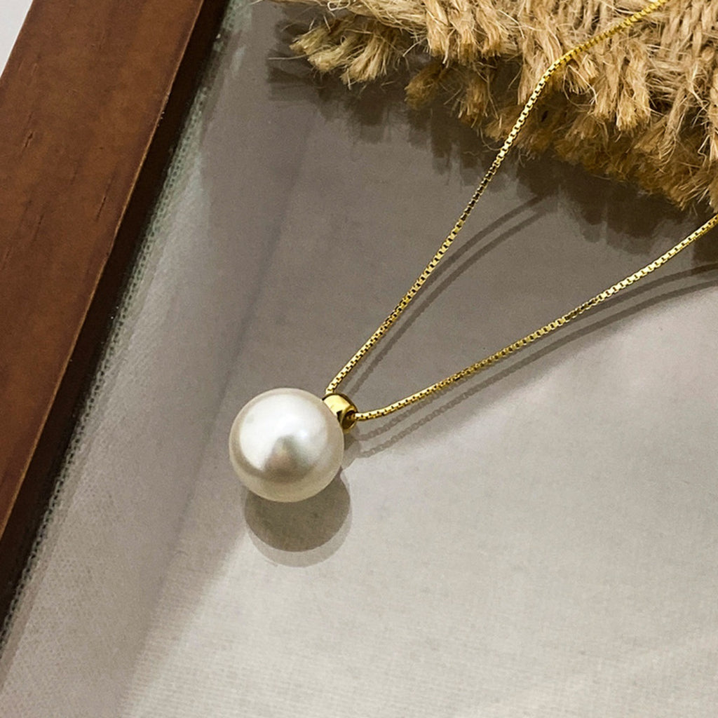 Pearl necklace with gold chain on a neutral background