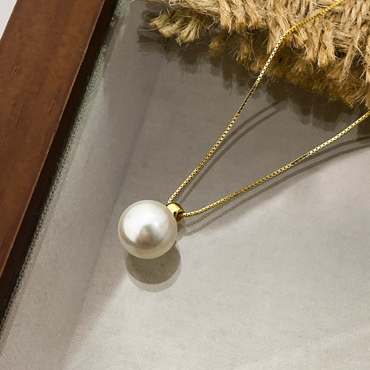 Pearl necklace with gold chain on a neutral background